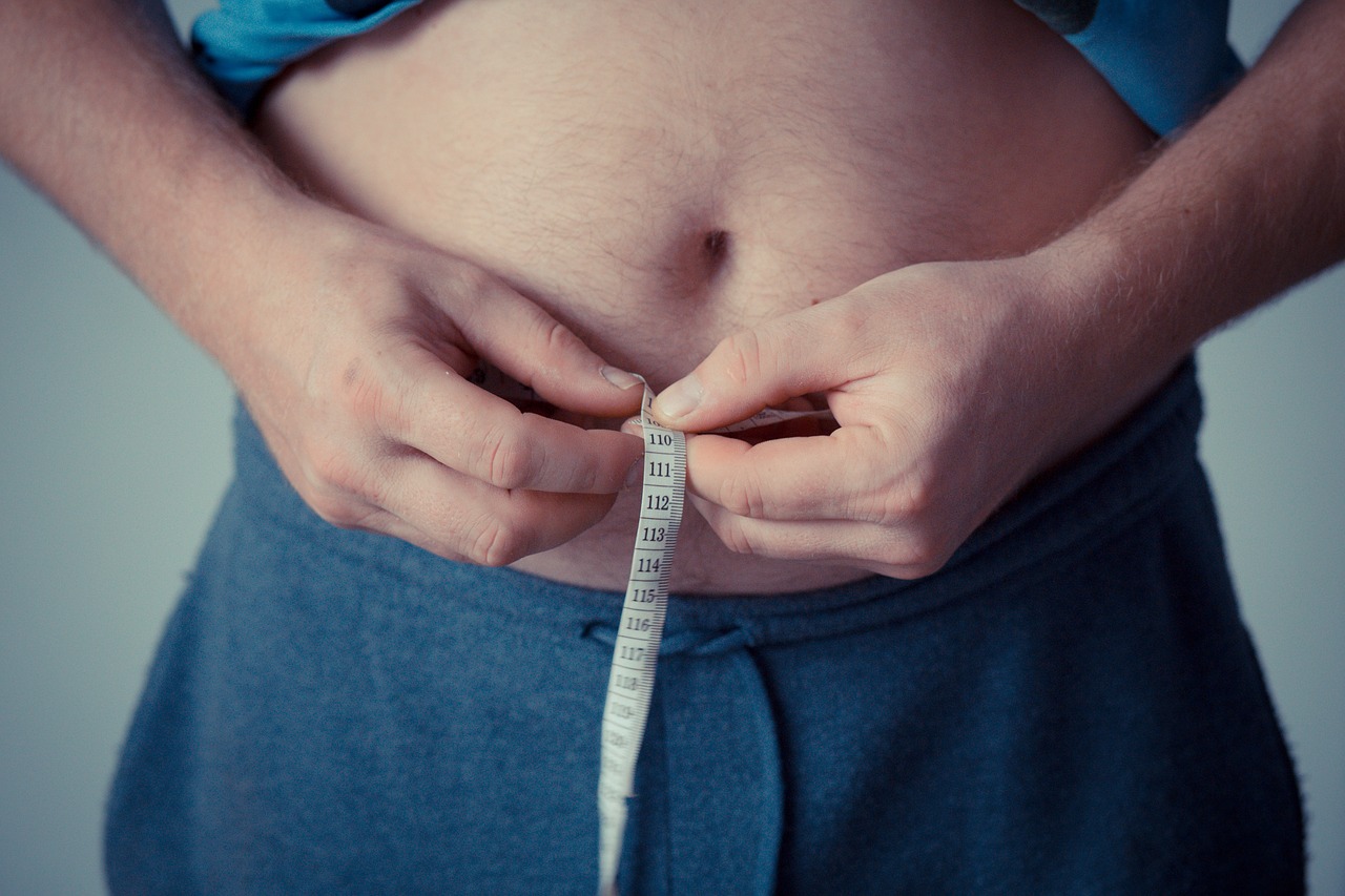 A man measuring his waist with a tape measure