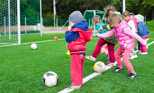 Children wrapped up warm playing football