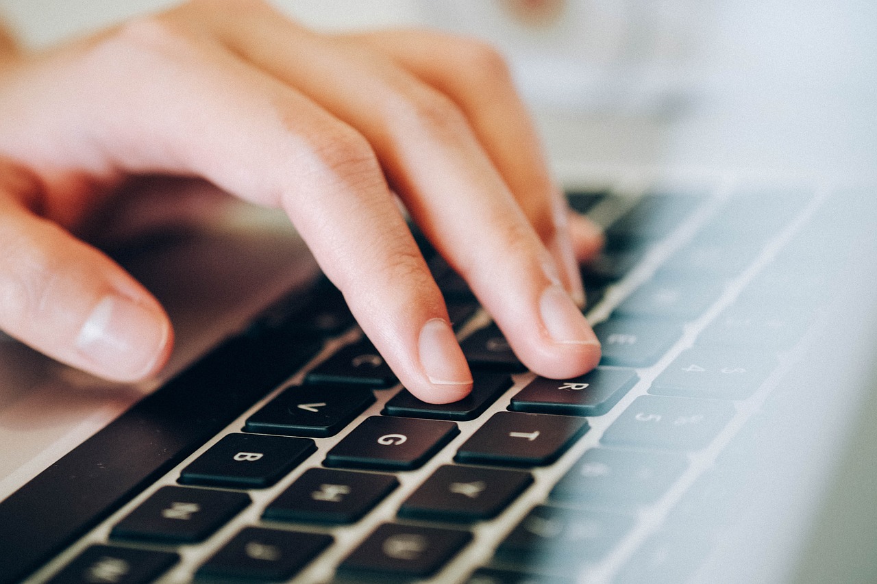 A close up of a hand resting on the keyboard of a laptop