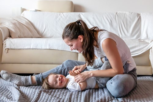 A mum playing with her smiling toddler