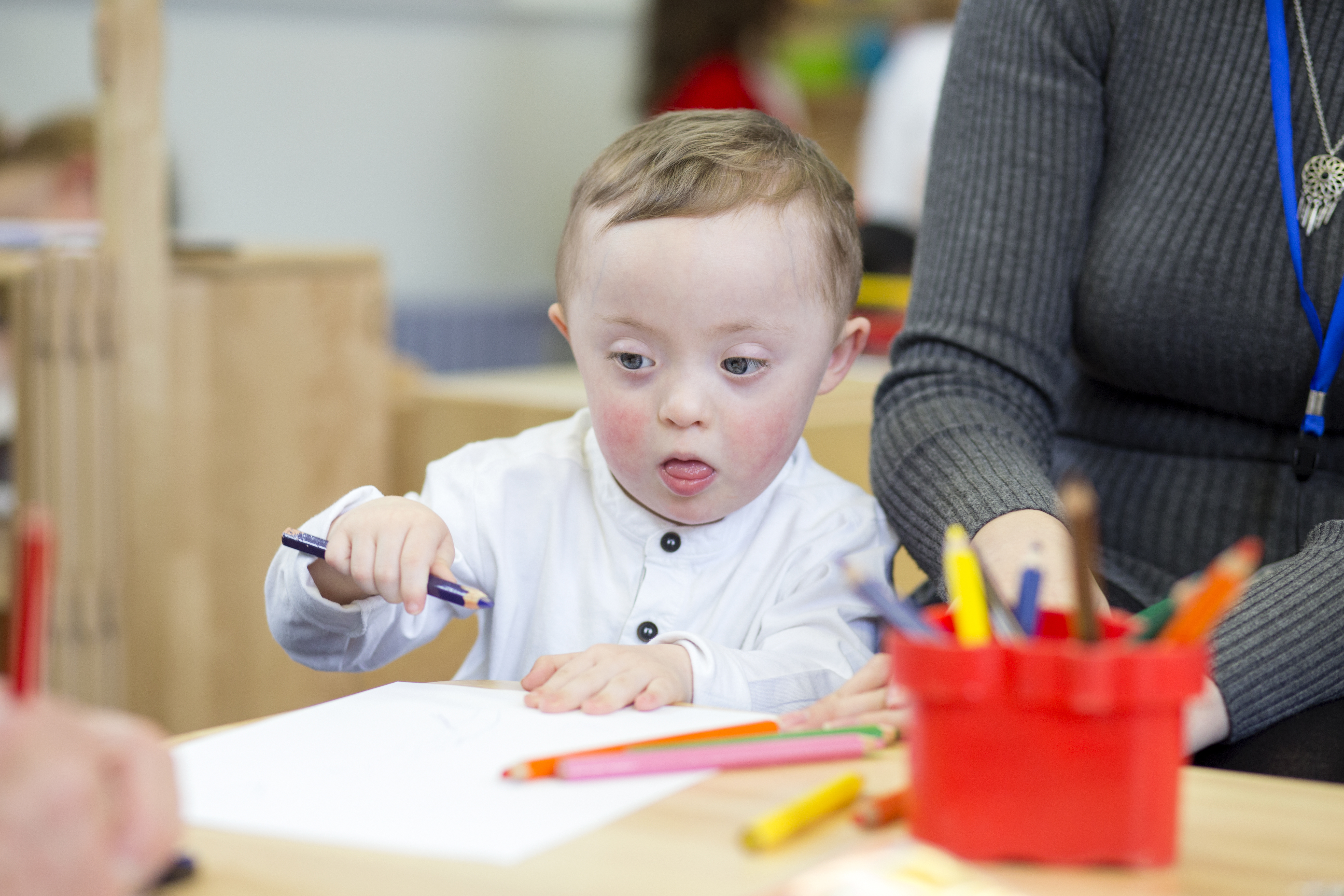 A young boy with Down's syndrome drawing a picture