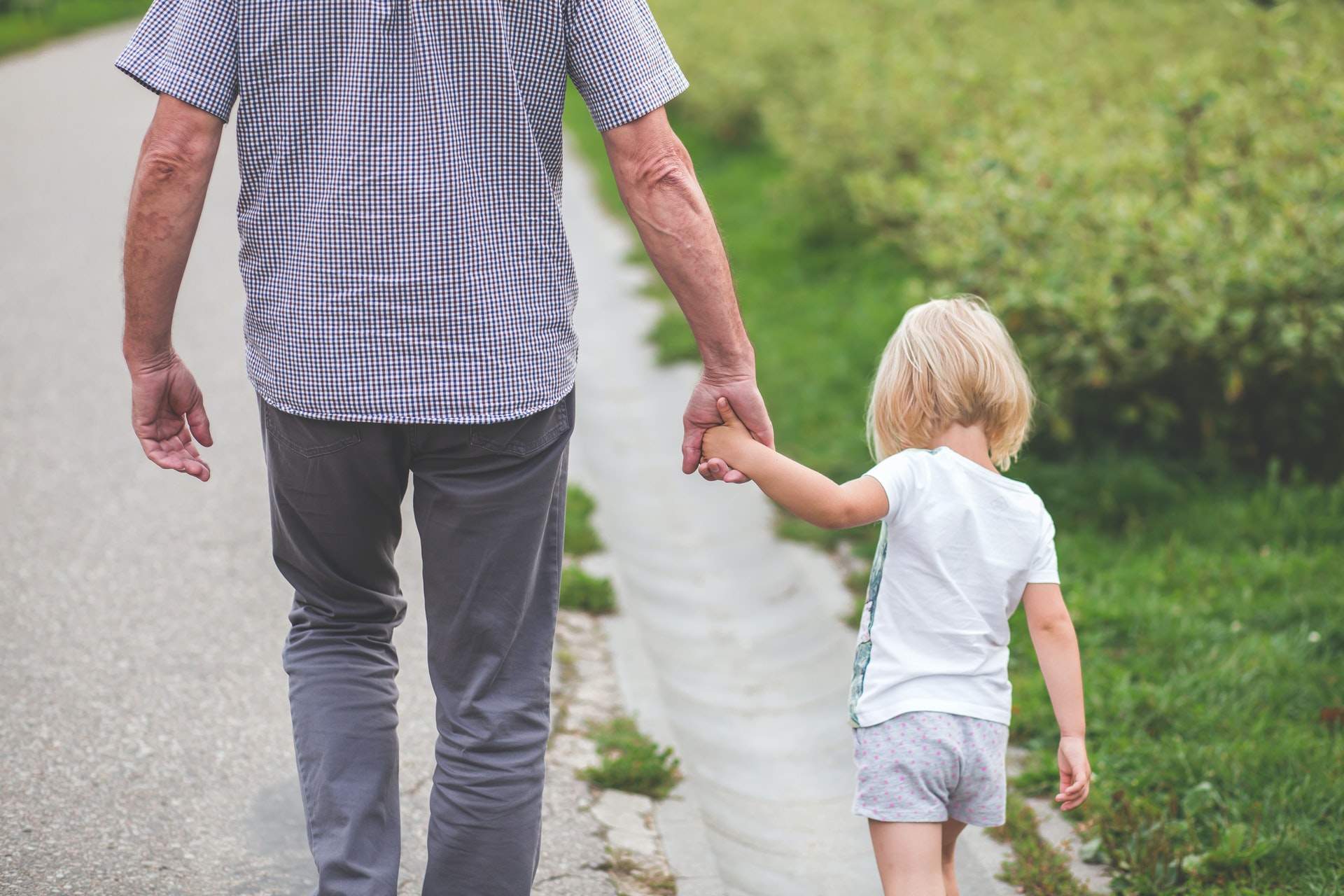 A toddler and parent walking together holding hands