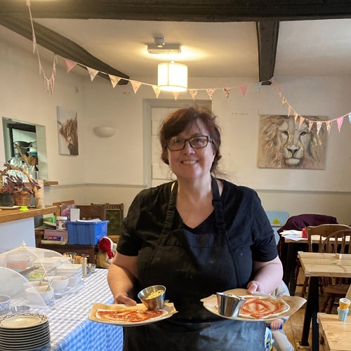 Kate at Lion cafe, holding a plate in each hand with a DIY pizza kit