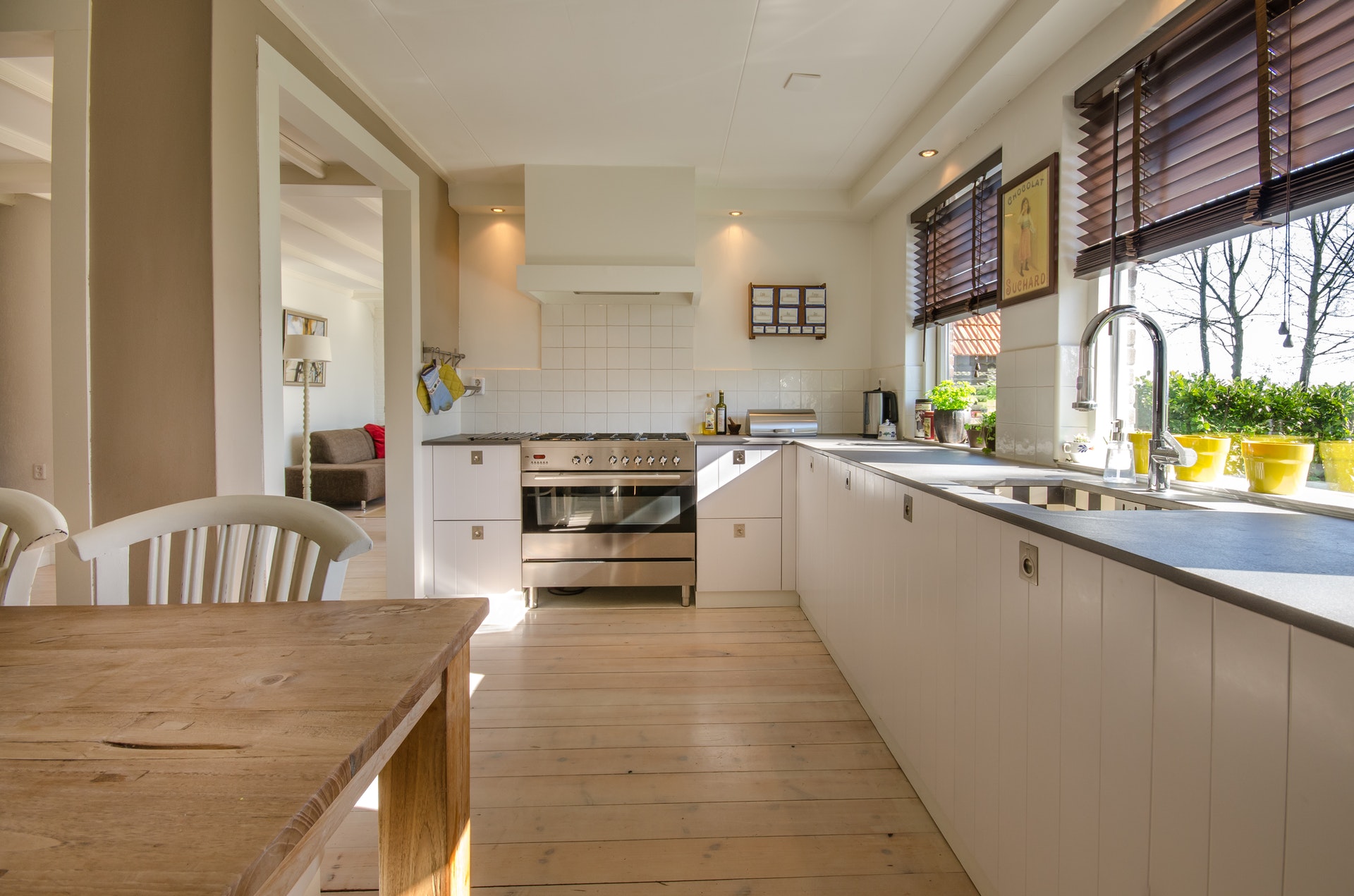 A kitchen with white cupboards and a wooden dining table
