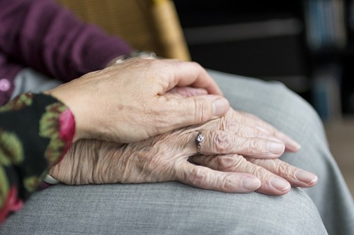 A younger woman placing her hand over the hands of an older woman