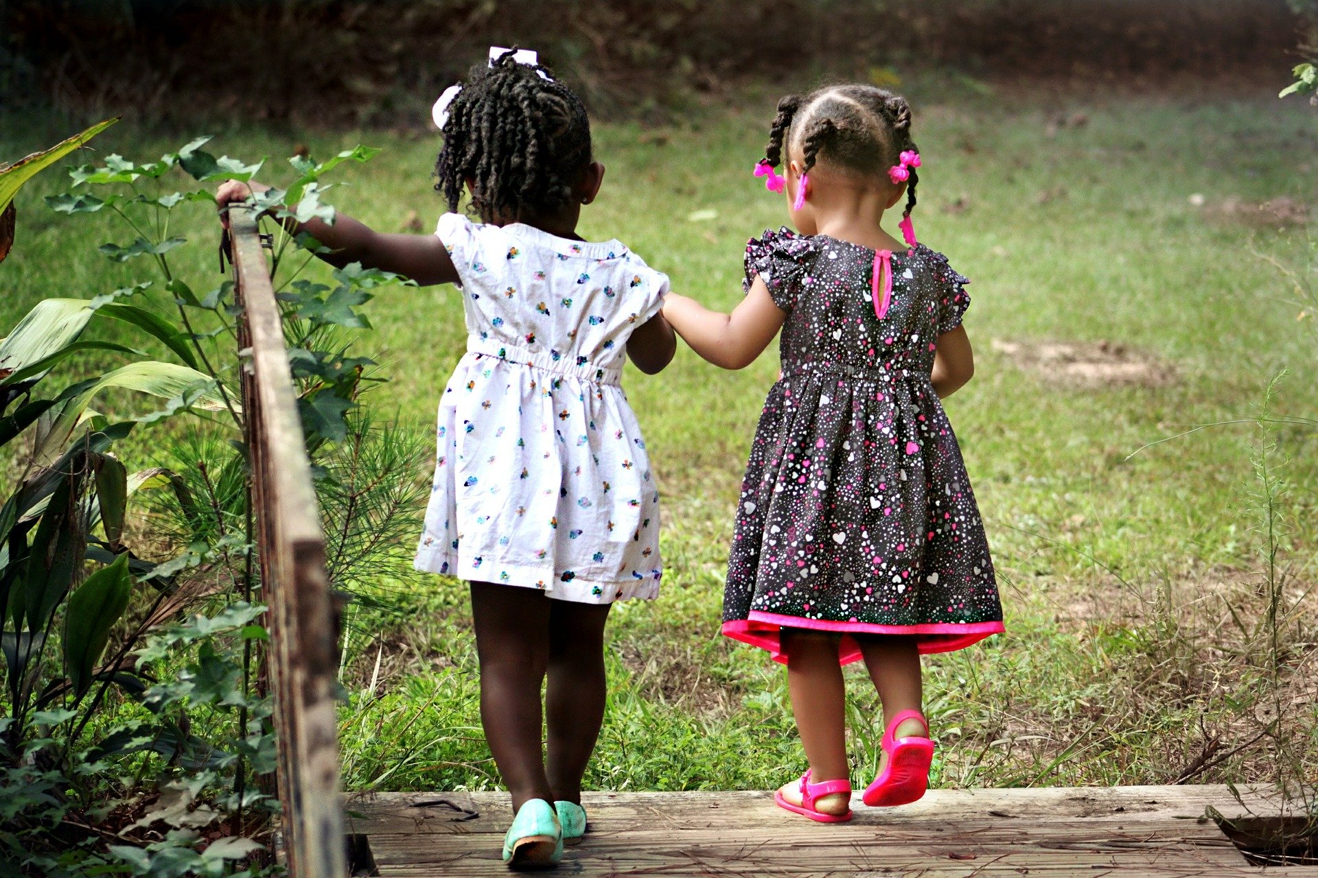 Two toddlers walking together, holding hands